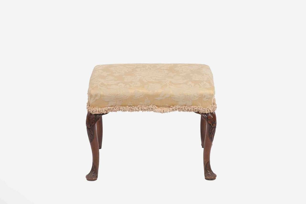 Mid-18th century George II mahogany stool, the over upholstered rectangular seat raised on cabriole legs each carved with stylized shell terminating on pad foot, circa 1755.