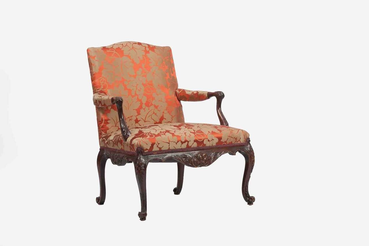 18th century mahogany library chair carved in the Chippendale style with square back. The chair has a beautiful carved frame. It is supported on a cabriole legs with acanthus knees and terminating in scrolled feet.