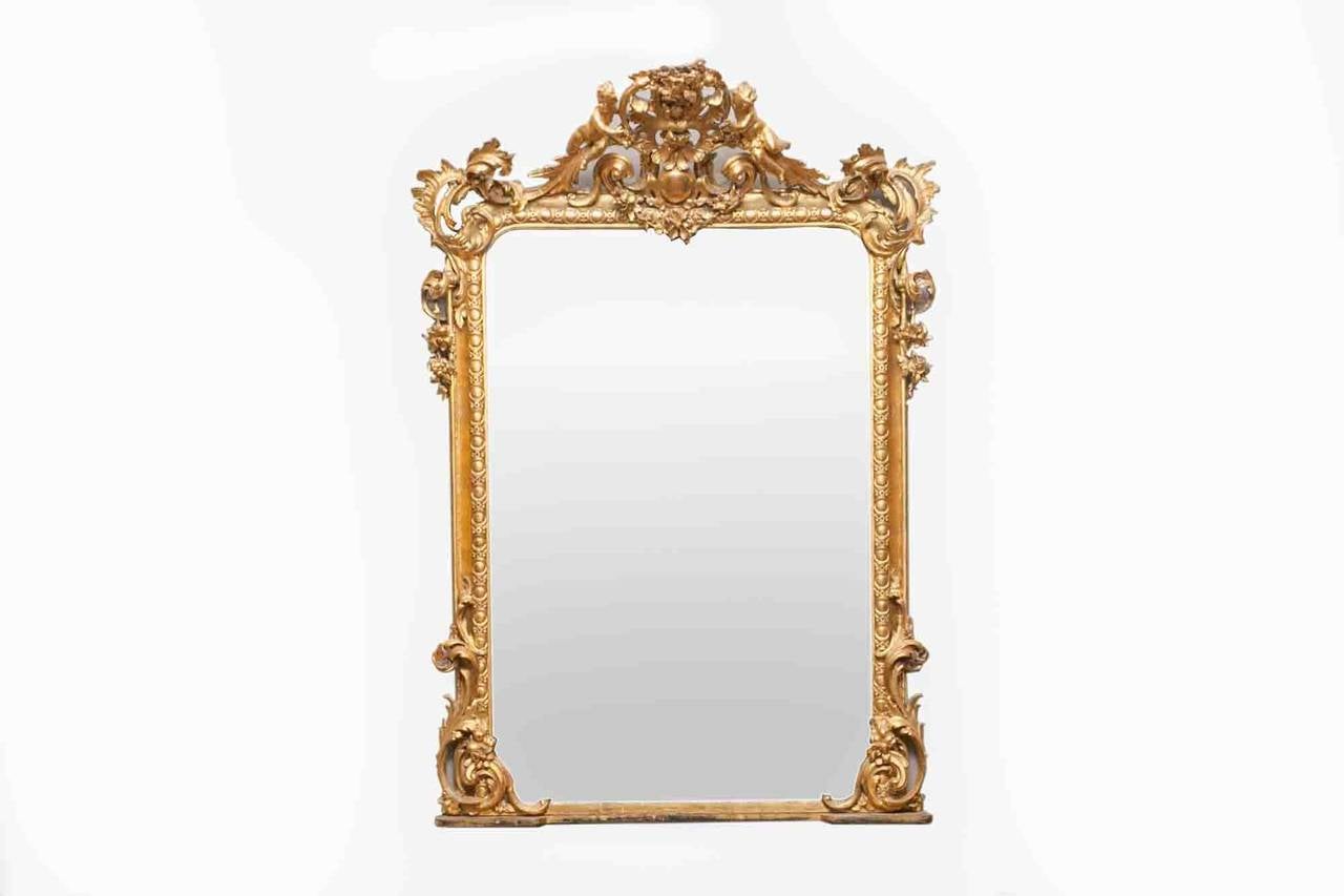 19th Century Gilt Overmantle Mirror, rectangular glass plate within carved giltwood scrolling foliate surrounded by a pair ofcarved cherubs