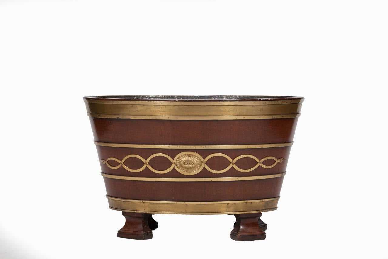A George III Brass bound lead lined Wine Cooler.  The ovoid tapering lead lined body with solid brass band on the upper lip with a decorative interlaced brass design around the mid section followed by a solid band at the base, raised on flared
