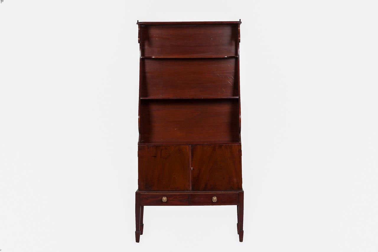 19th Century William IV miniature waterfall mahogany bookcase.  The shaped and moulded bookcase over double doors on two short drawers on square tapered legs ending in spade feet
