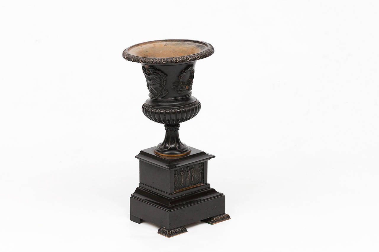 19th century bronze campagna shaped urn. Raised on square plinth depicting a classical scene.