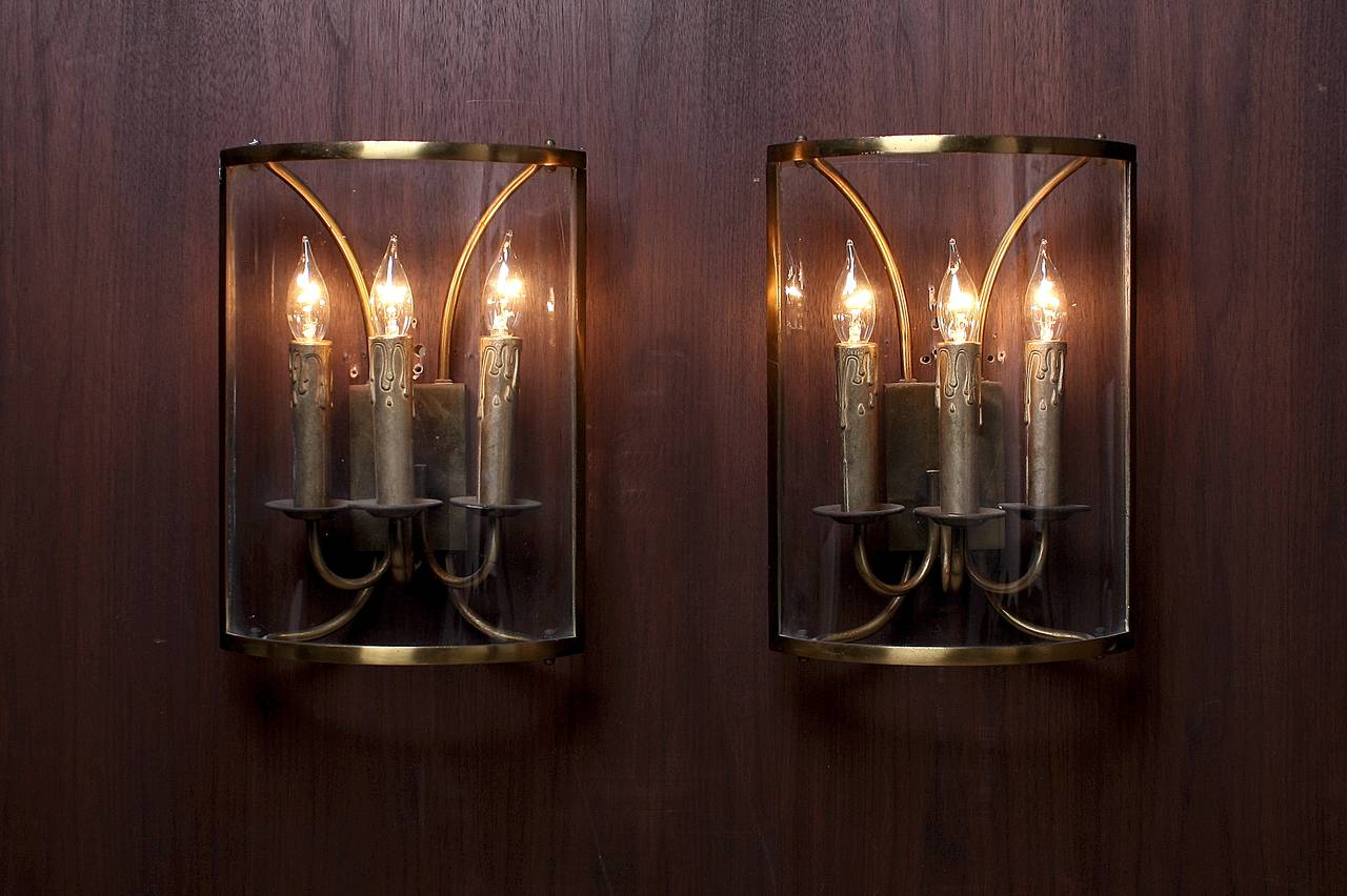 Beautiful wall lantern sconce with three brass candle pillars ensconced in a curved glass shade. Very Classic and clean lines.

One of four available. Sold individually.