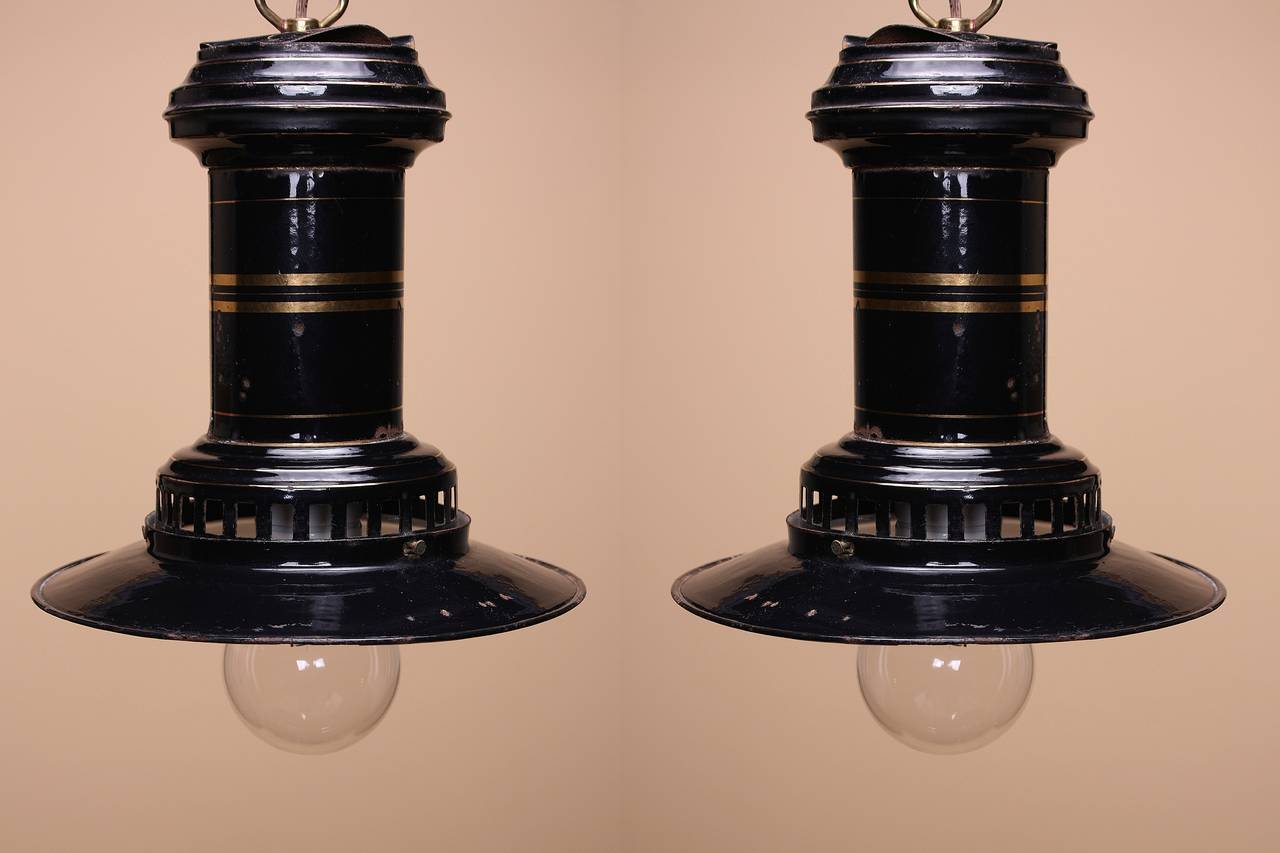 A pair of black enameled Industrial pendants with gold accents. These pendants have an incredible patina and an amazing Silhouette.