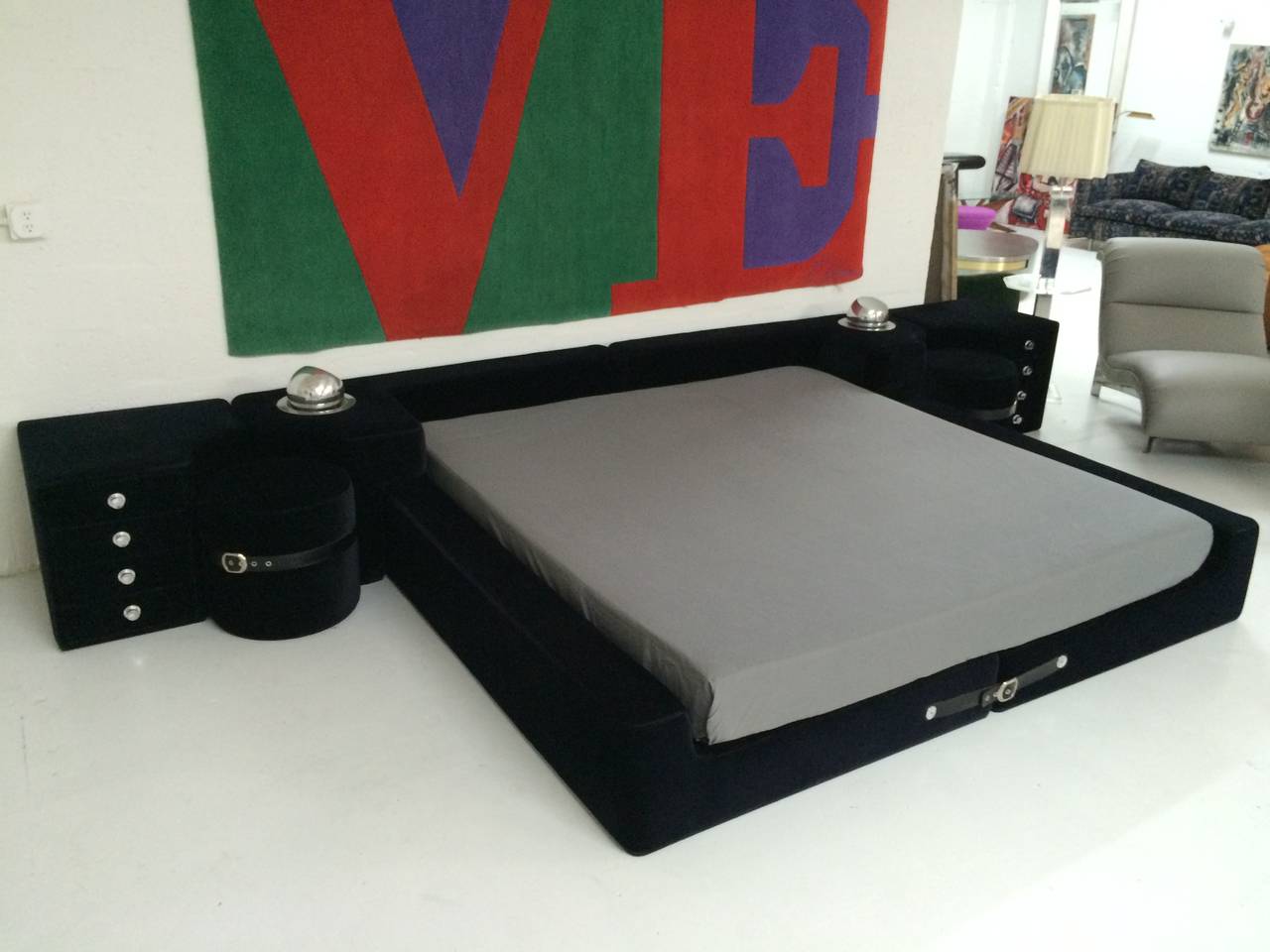 Ink colored (blue-black) velvet king-size bed designed by Guido Faleschini and manufactured by i4 Mariani exclusively for the Pace collection, with black leather straps and chrome buckles, integrated nightstands, ottomans, and lights.