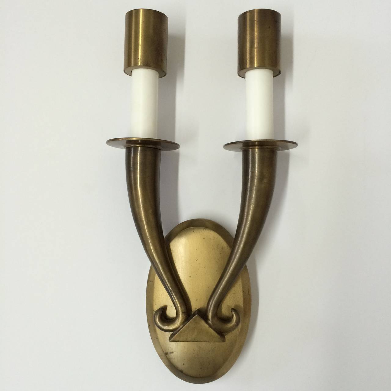 Art deco pair of wall sconces rendered in un-lacquered patinated brass in the style of Ruhlmann.