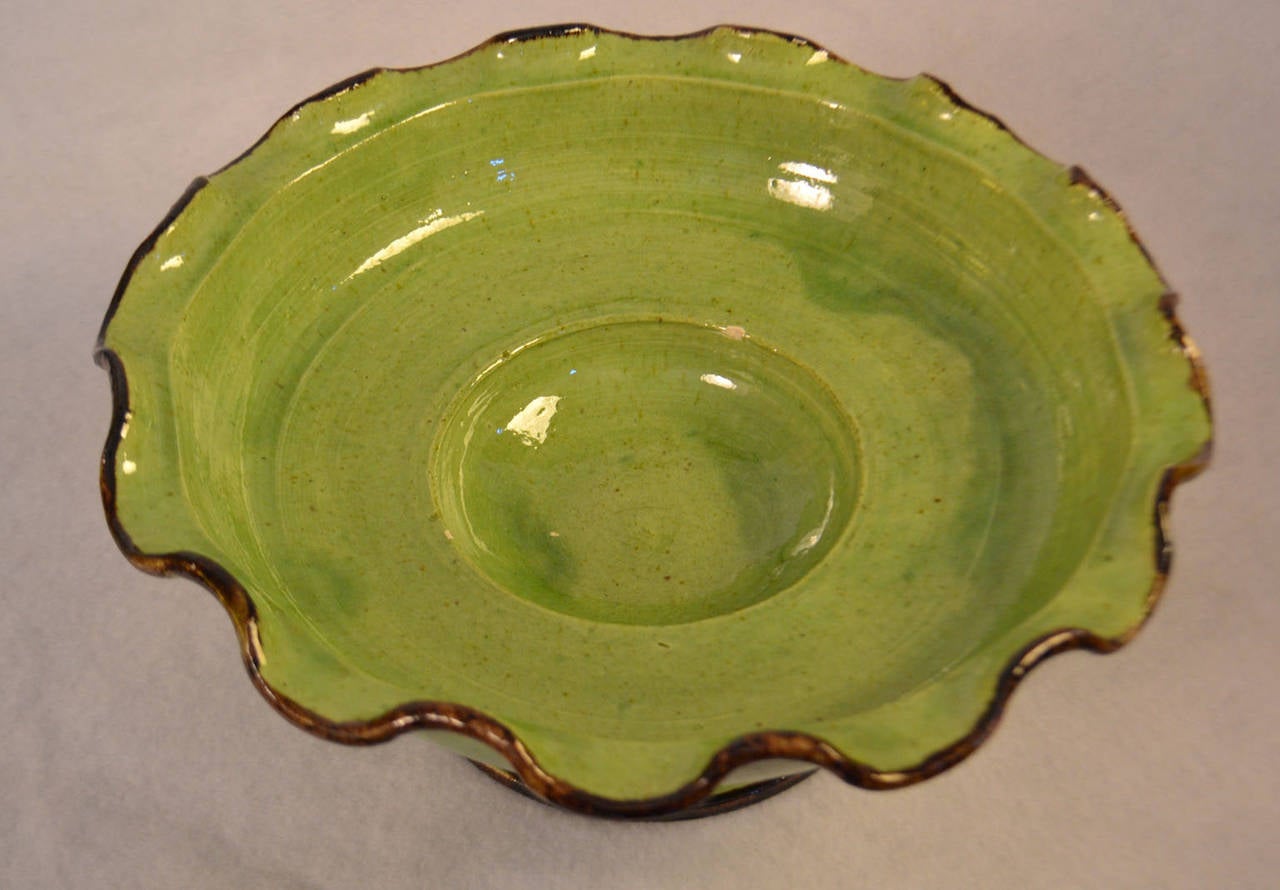 Mid-20th century green earthenware cake plate with wavy edge design.