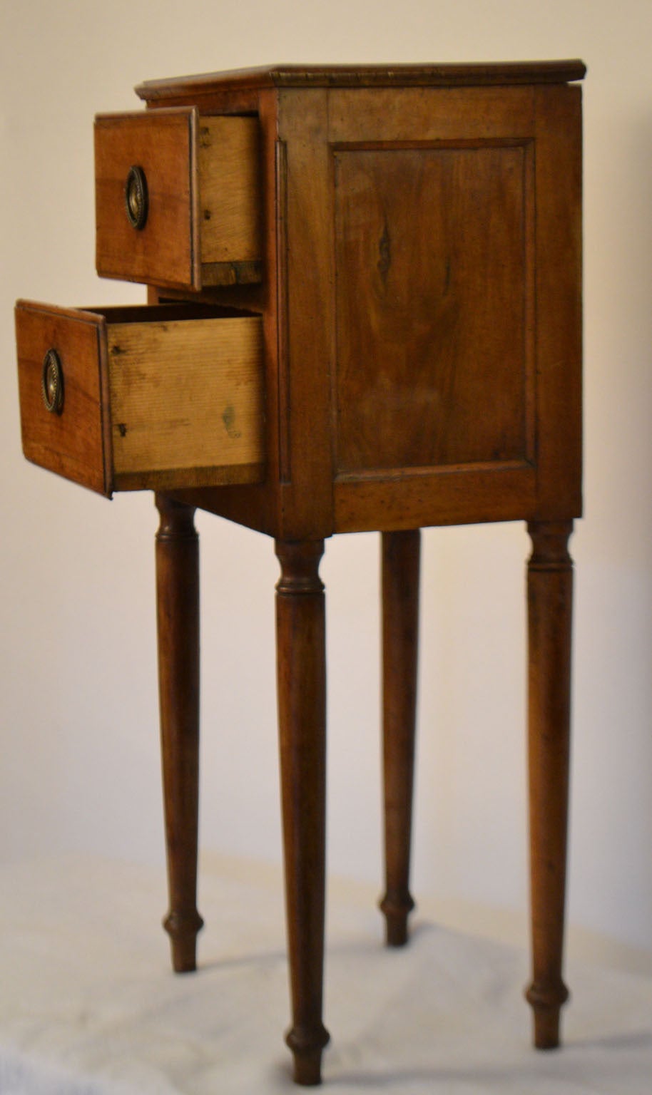 Late 18th century Directoire nightstand with two drawers with beaded circular keyhole plates and simple baluster legs.