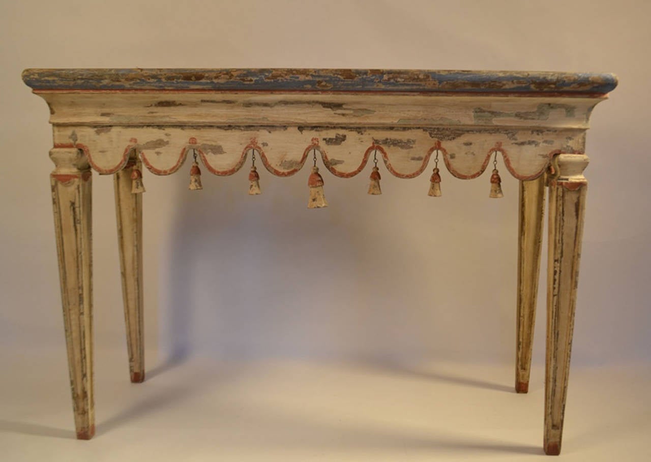 Italian console table with carved and scalloped apron with painted red border and hanging wood tassels, resting on legs en gaine. Legs and tassels are newer and not antique, top is period (circa 1780).