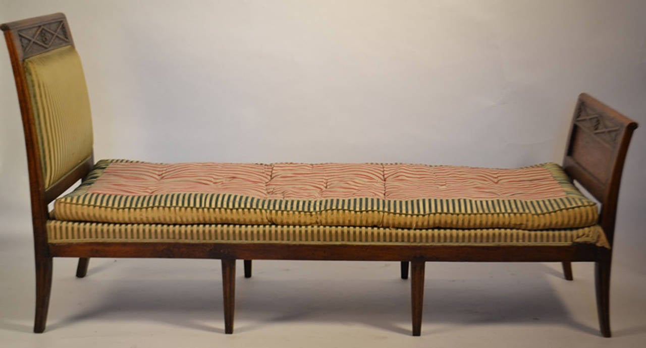 Directoire period daybed en Recamier, with head and foot board presenting a diamond shaped lozenge motif with a central daisy, on eight fluted legs, the side of the head and foot board panels presents very finely detailed geometric carving.