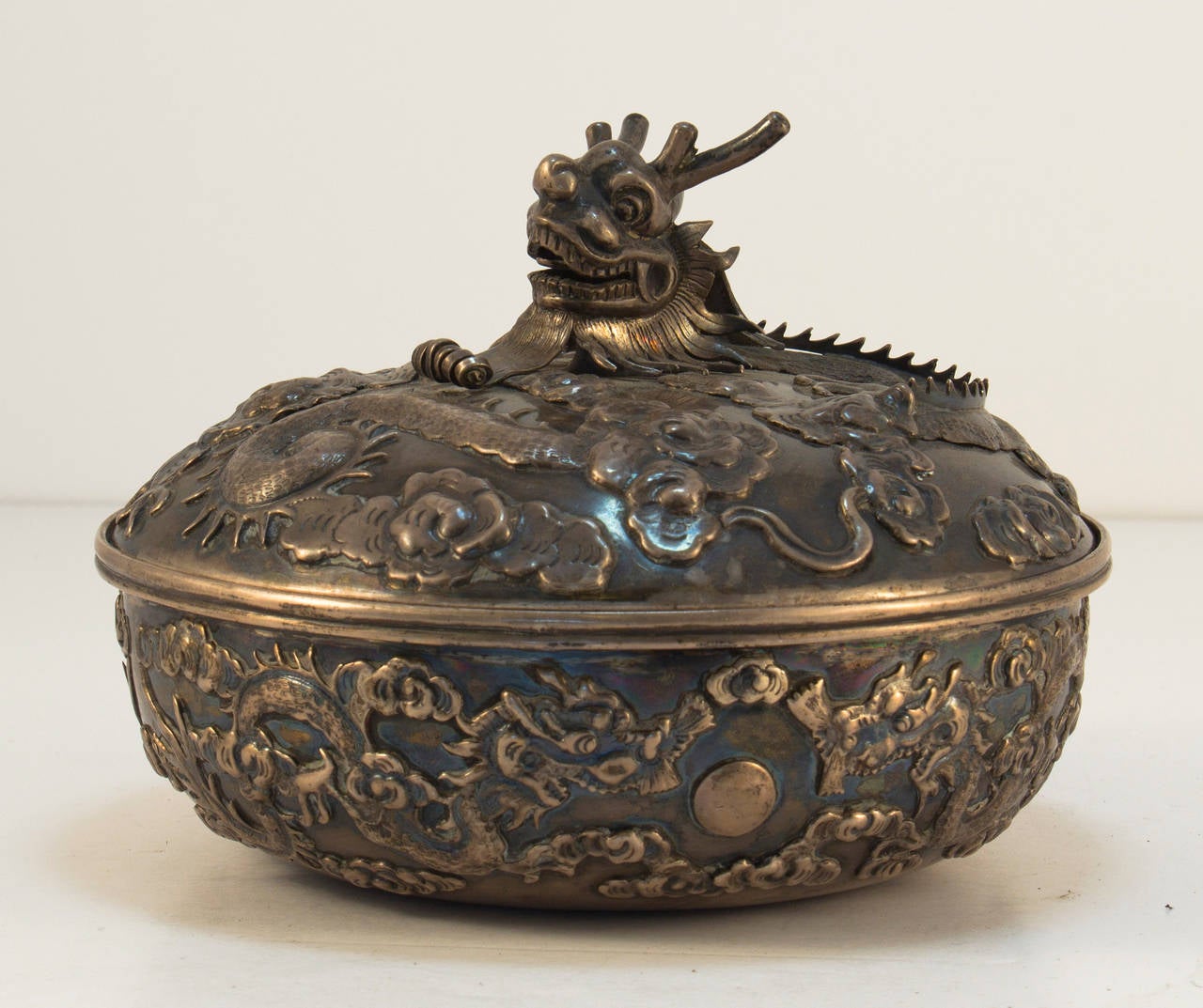 Chinese export silver canister, Hong Kong, late 19th century, Wang Hing & Co., makers, also bearing Glasgow import mark for 1895, round, chased, embossed, the sides with writhing addorsed dragons reaching to the jewel of immortality amidst the