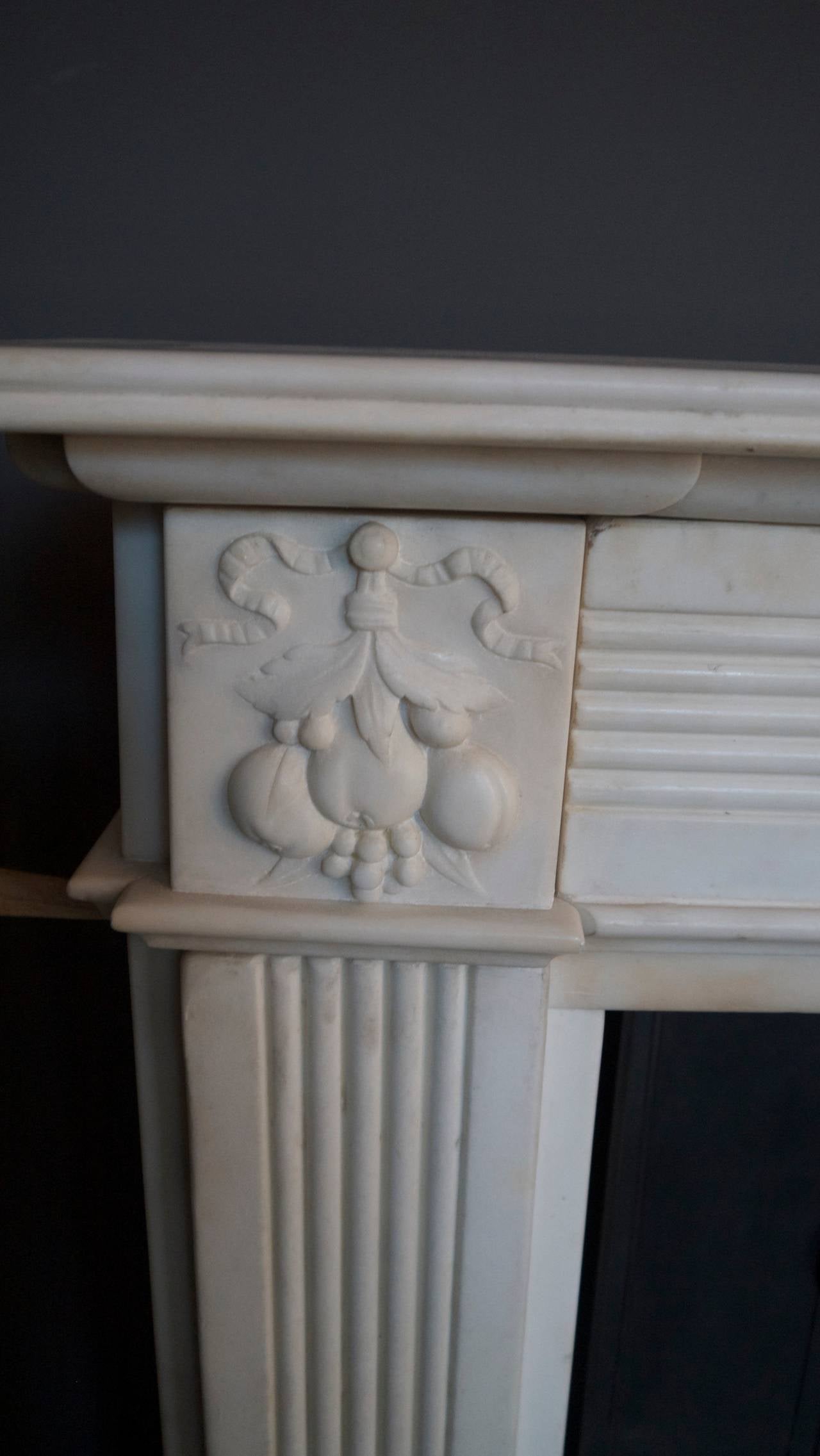 Original exceptional 18th century statuary white Georgian marble surround with a fruit bowl center plaque, carved cornerblocks, reeded legs and frieze and a birds beak shelf.