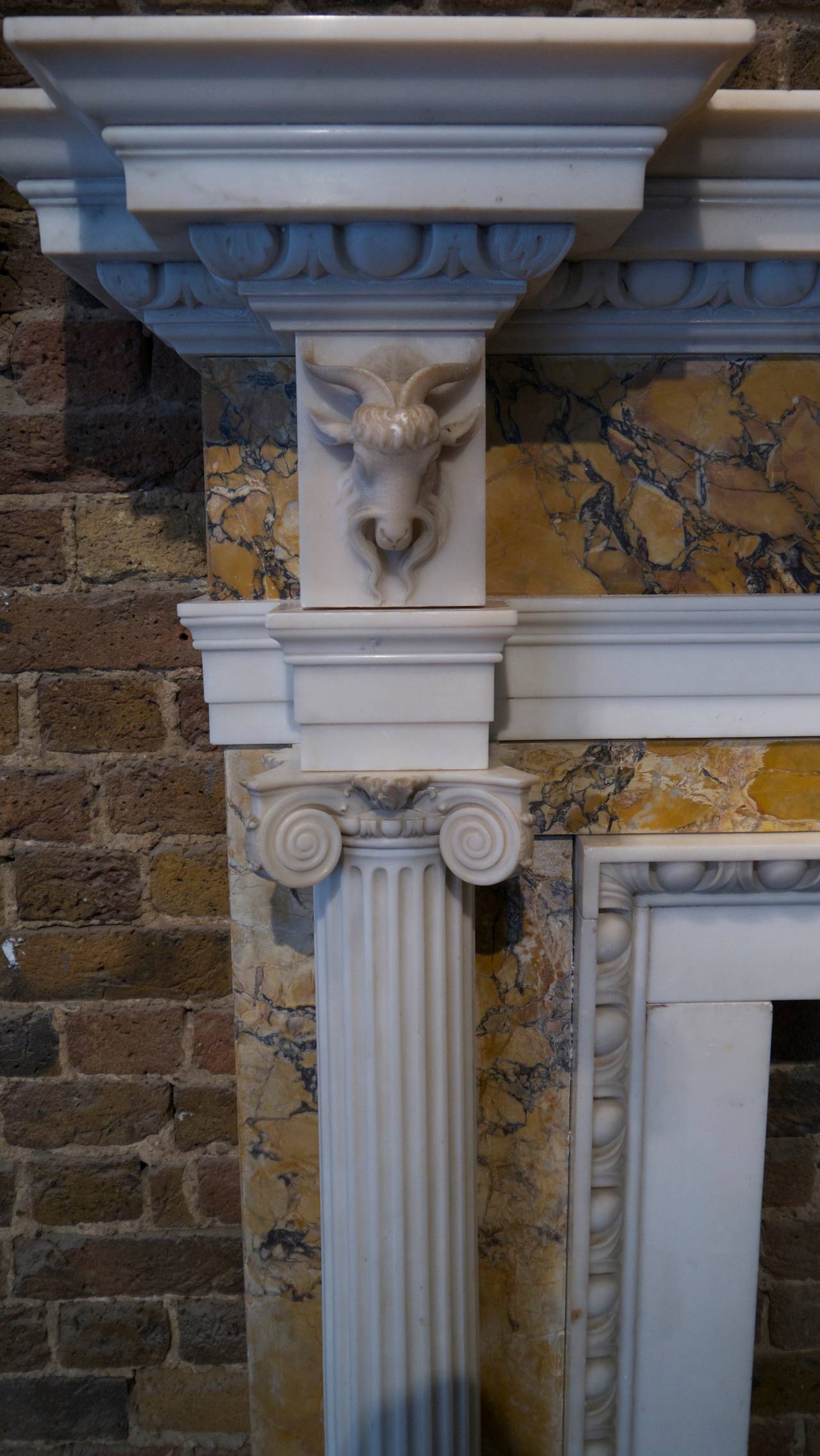 Antique George III white statuary white and Siena marble surround with a finely carved center plaque depicting a scene from the story of Androcles and Lion. The frieze is supported by a pair of freestanding, fluted, ionic columns under goat mask