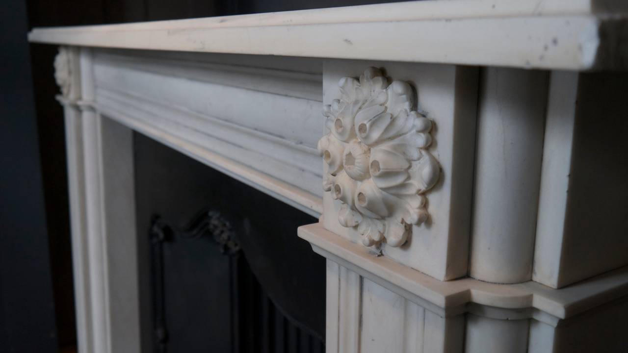 A Georgian style aged statuary white marble fireplace with beautifully carved corner blocks. Measures: Opening 40 x 40.
