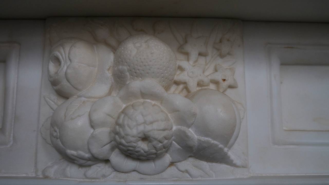 Original statuary white Georgian marble surround with carved fruit corner blocks, a center plaque depicting flowers and fruit and acorns on the legs. Berners Street. Opening 37.5 W x 37.25 H.