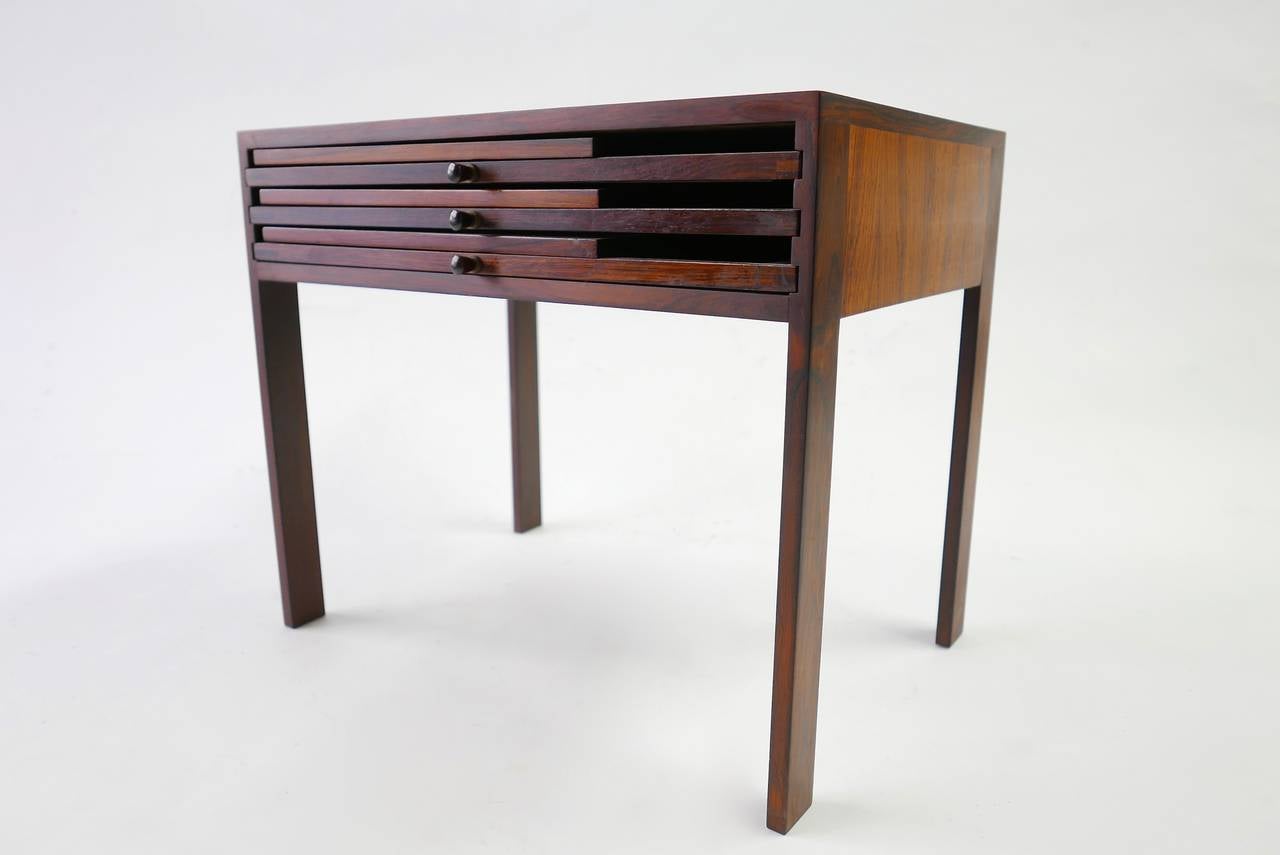 The handsome occasional table houses three folding drink tables. Each measures 17 W x 16 D x 16.5 H inches. A sturdy design in rosewood perfect for entertaining. This set is signed with a label to the underside.