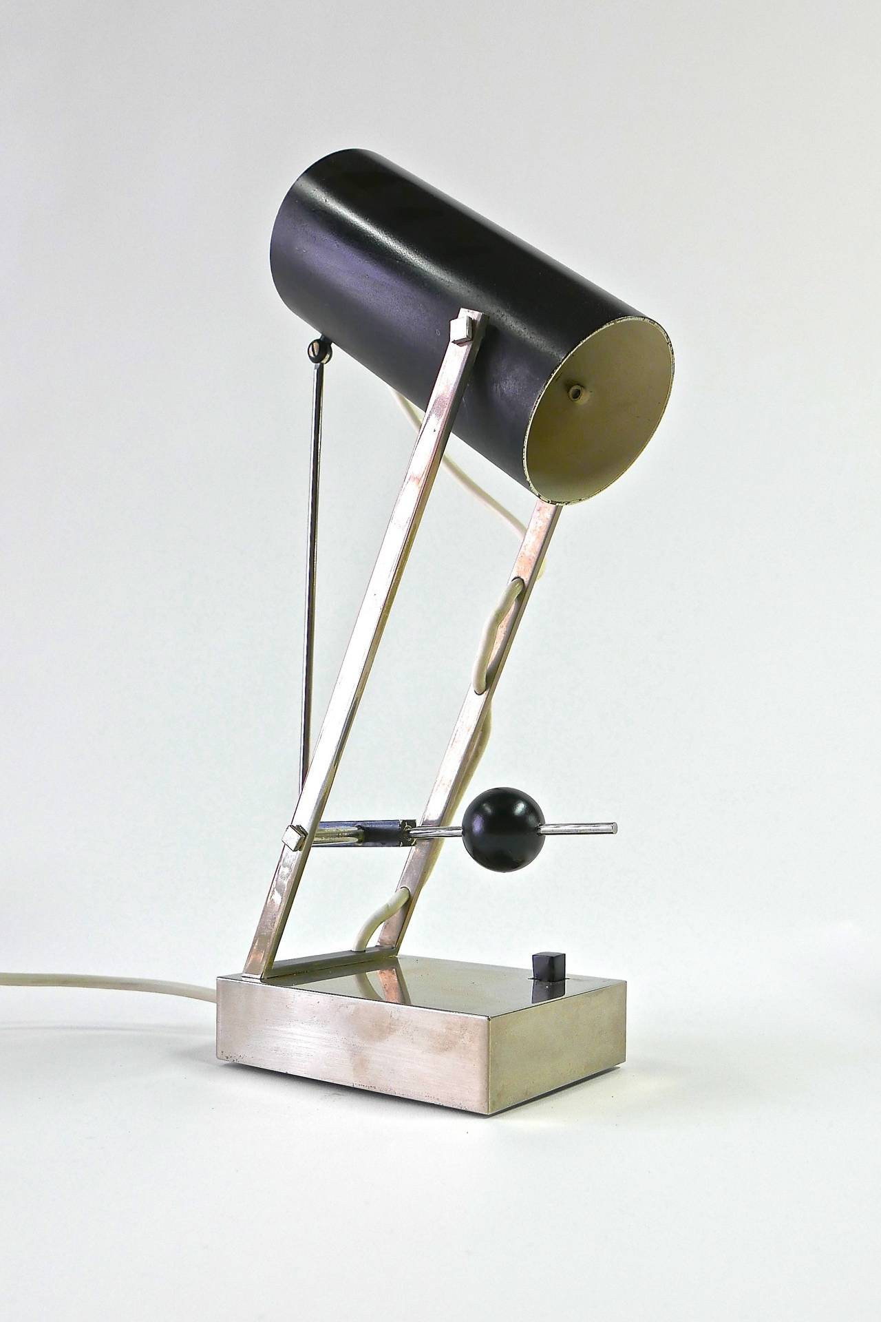 Adjustable table lamp with constructivist form designed by Angelo Lelli and produced by Arredoluce, c. 1968. The cylindrical visor pivots on a fulcrum.  The ball handle lifts the shade up and down on a 35-degree ark.  Retains manufacturer's decal –
