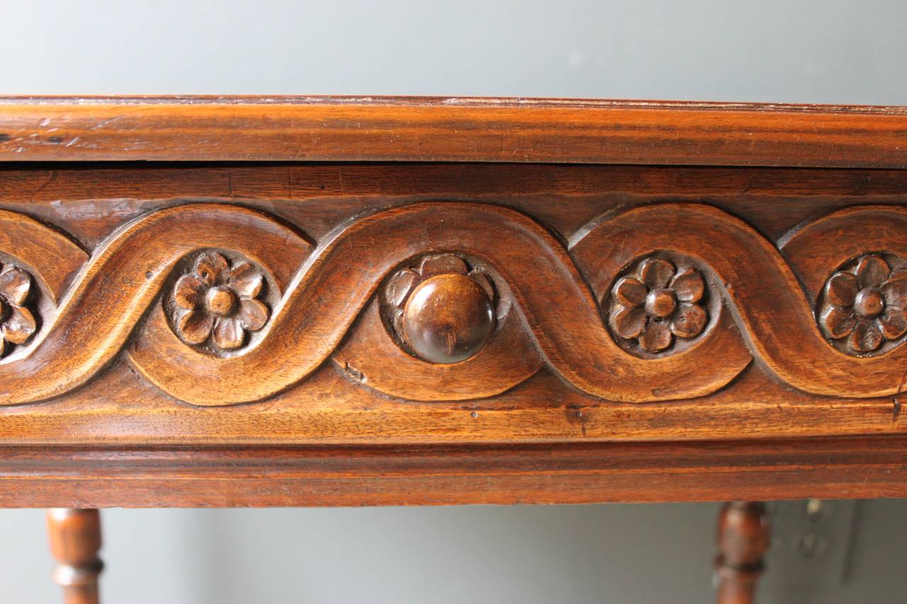 Lovely carved walnut Louis XIII table with one drawer. The drawer fronts and two sides have a wonderful swirled carving and rosettes. The table has turned legs and stretcher. France, 18th century.