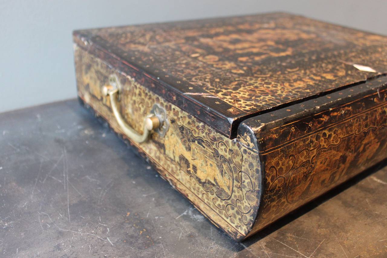 Beautifully detailed and large Chinese export lacquered in gold writing box. This exquisitely detailed box features intricate design and lacquer work. The box also contains several lidded containers with small knob handles made from bone or ivory.