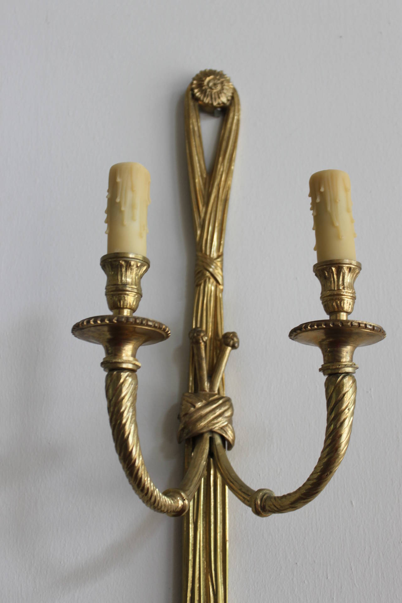 Pair of French brass neoclassic sconces each with two arms with looped tassel trim detail.