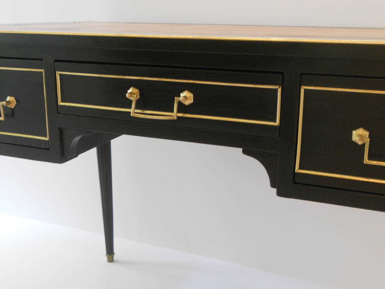 Stunning and elegant French ebonized mahogany writing desk with cognac leather writing surface and two pull-out extensions. The desk has three operable drawers and three false drawers on the opposite side so that it appears finished from all sides.