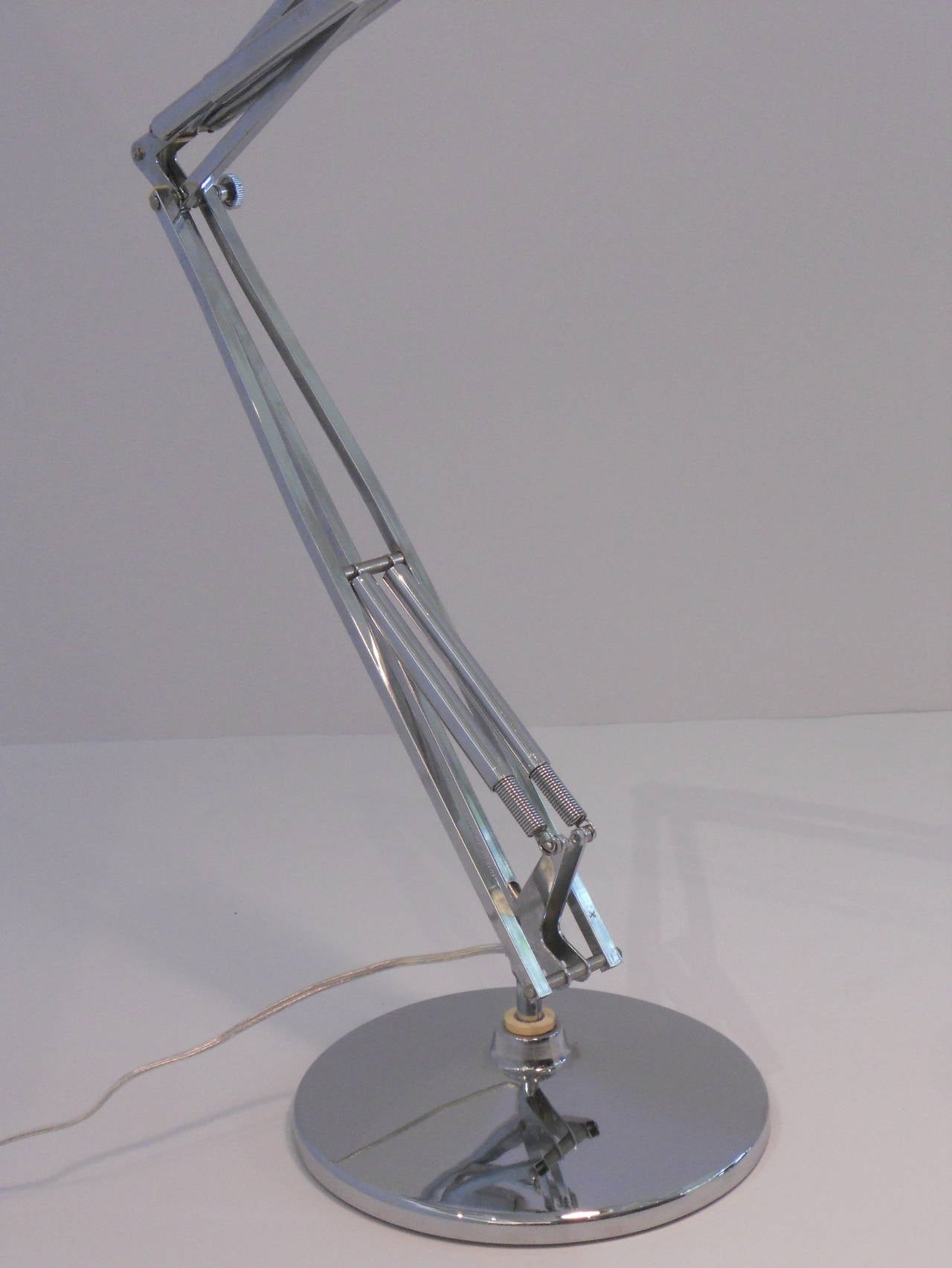 Exceptionally heavy articulated chrome desk lamp with a modern chrome shade. Lamp is on a weighted chrome base and has spring construction on the articulated arm with an on/off switch at the top of the metal shade.