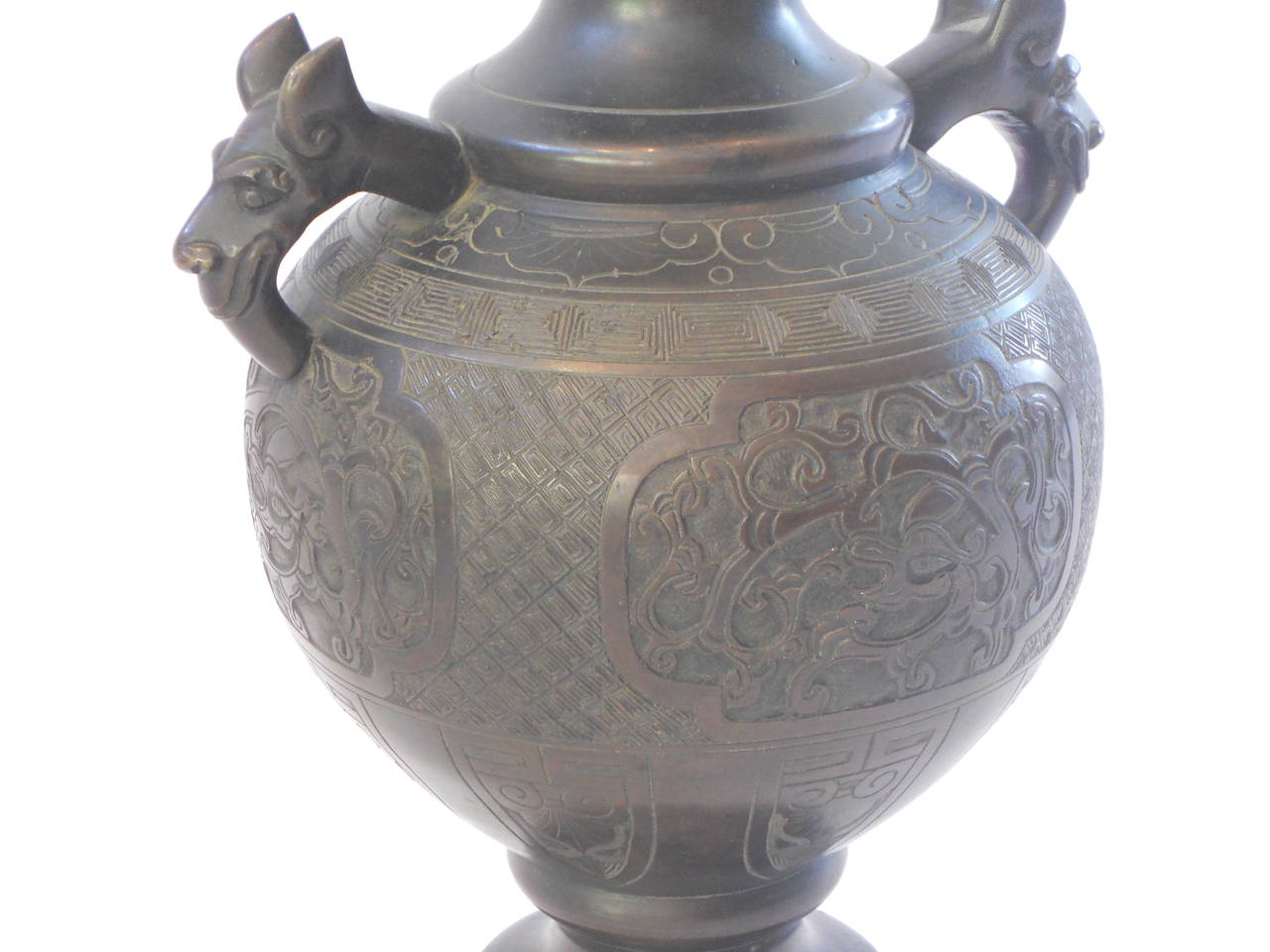 An early 20th century bronze vase on a wooden stand with dragon handles and beautifully detailed decoration throughout.