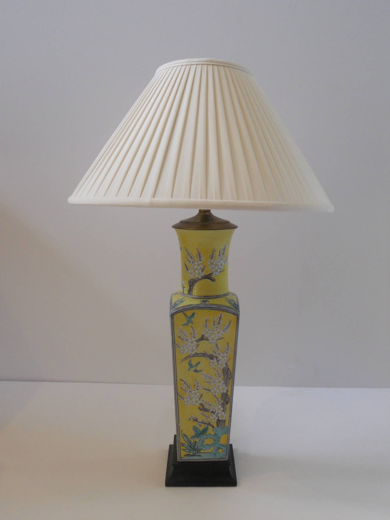 A tall, slender Chinese vase with blossom decoration. This piece is hand-painted in shades of pale green, white and soft brown on a yellow field. The vase is mounted on a square wooden base with new wiring and a new pleated, silk shade.

Shade