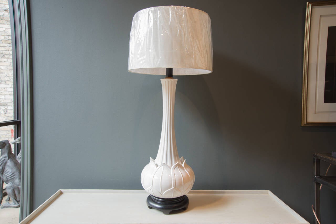 This very tall and grand lamp is made from a beautiful white vase in the shape of a lotus at the base. The lamp has been newly wired and includes a dark wood plinth base as well as a new shade. The base of the lamp is 12