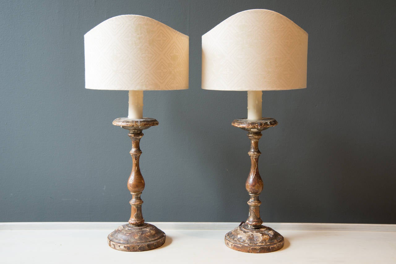 Questa coppia di lampade è composta da candelieri in legno intagliato italiani del XVIII secolo con tracce della doratura e della vernice originali. Le lampade sono state recentemente elettrificate con un filo francese che corre lungo la parte