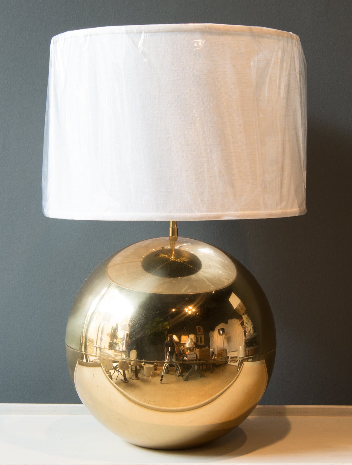 Brass Mid-Century sphere-shaped table lamp attributed to Karl Springer. Lamp base is a large brass sphere with a seam in the center. The lamp includes a new shade. The height to the top the shade is 27