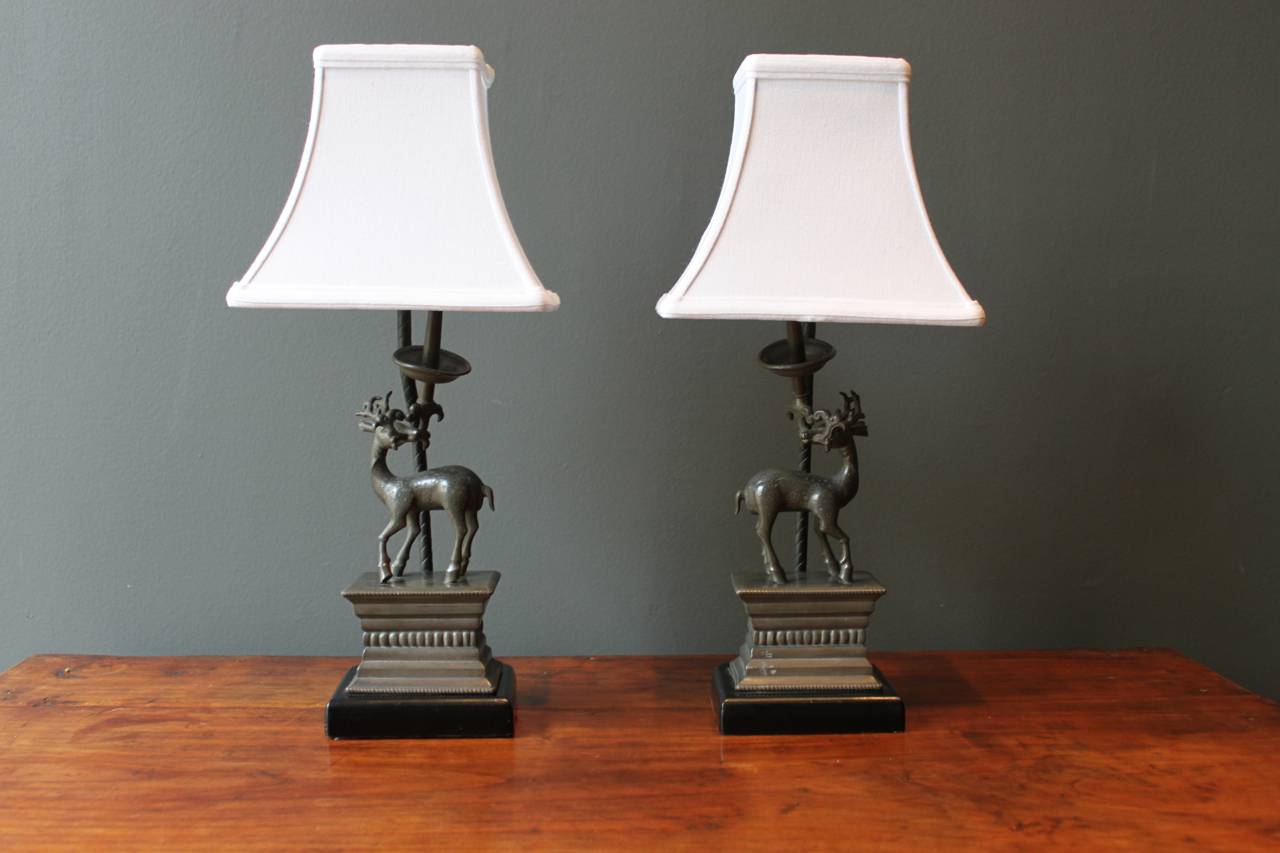 Beautiful and rare pair of Chinese antelope oil lamps mounted and wired as lamps in the early 20th century in the Ming style. 
The pewter oil lamps as a pair feature opposing deer on ebonized wood plinths. The bodies feature an etched floral design