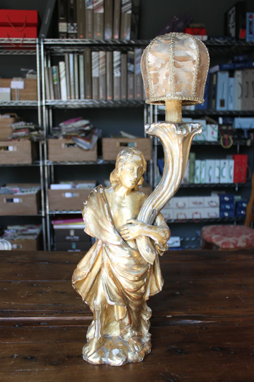 Rococo carved and gold giltwood figural angel candleholder wired as a lamp. The angel figure is draped in a robe and holding a cornucopia-form candleholder, Italy, 18th century the angel has a beautifully carved face, long hair and a robe. The
