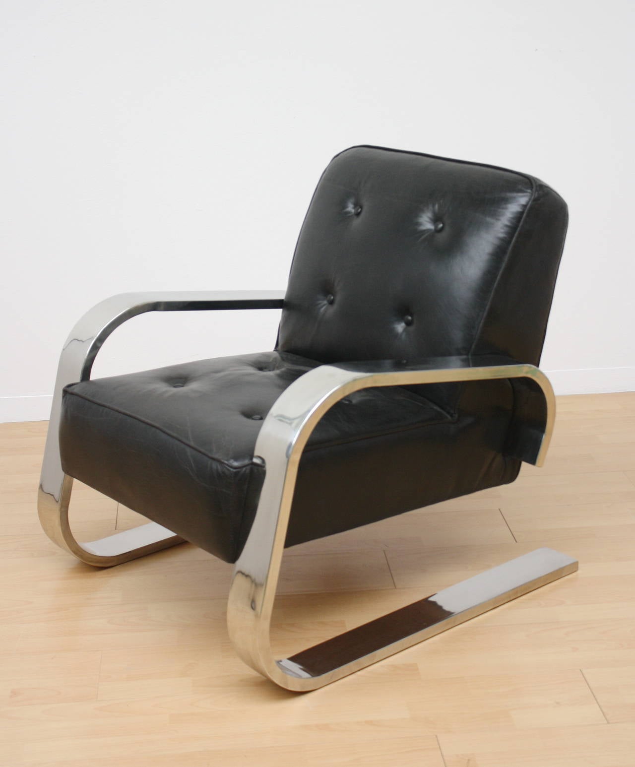 Cantilever lounge chair with black leather and width steel armrest and leg.