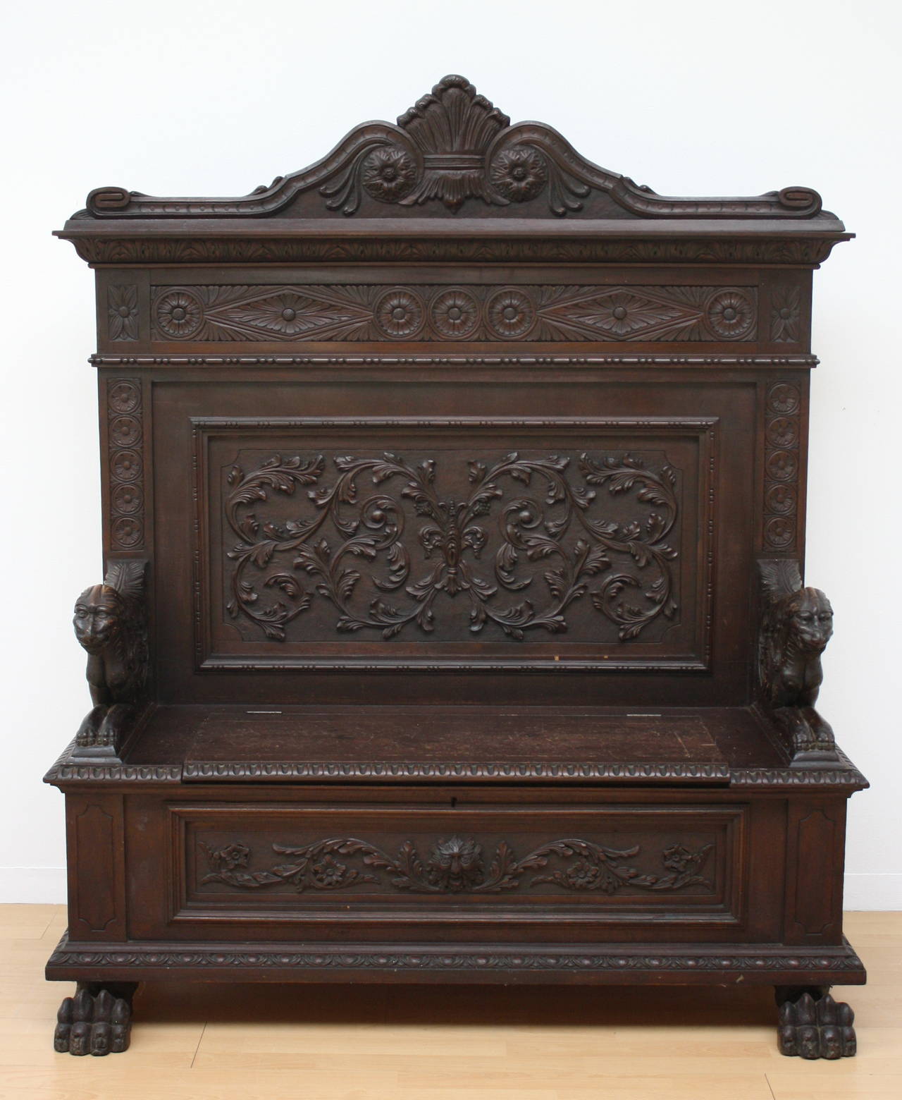 Well carved hall settle with carved Lion arm rests. In the front Lion-paw feet
Hinging seat for storage area.