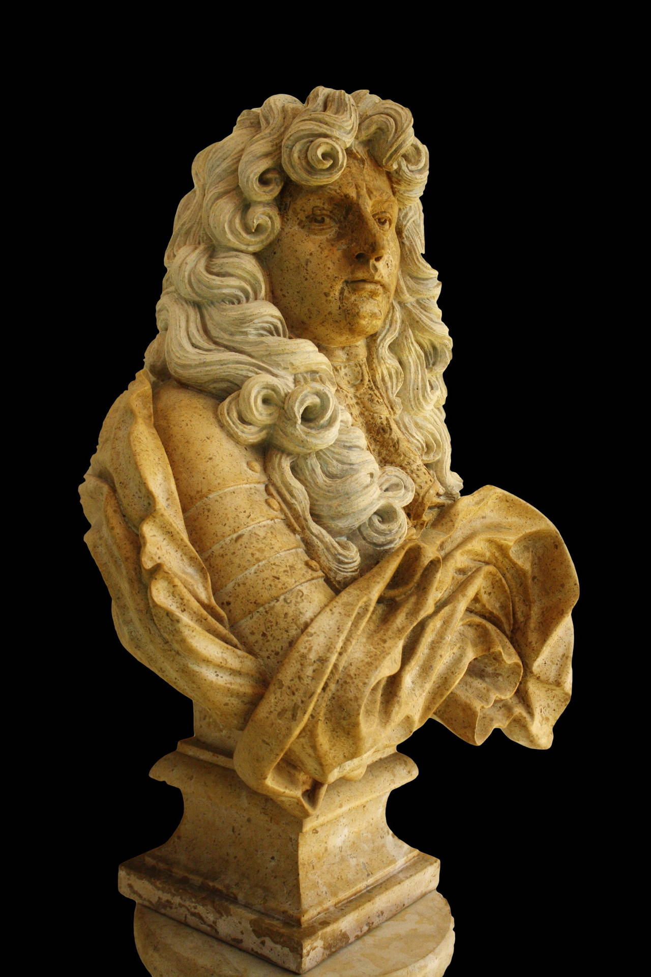 A Masterpiece of a Travertine bust. The bust presents the King Louis XIV in a lace collar and flowing cloak. He Looks away from the Viewer, as if purposefully avoiding his gaze. His wig seems to envelope his head and suggests the flaming locks of