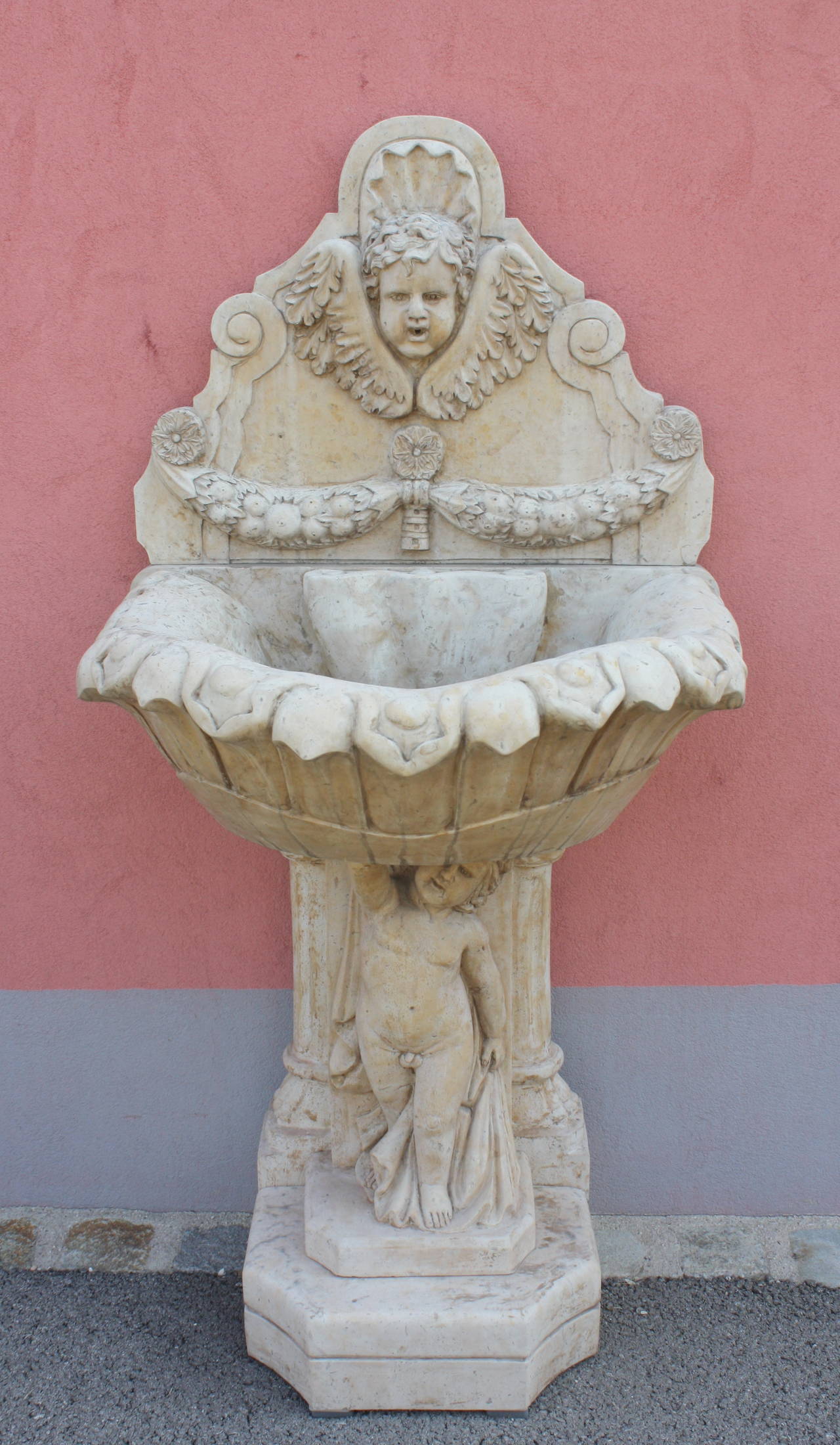 Lovely carved marble fountain. Angel face gargoyle, base with Putto Holding the carved bowle. Beige Marble.