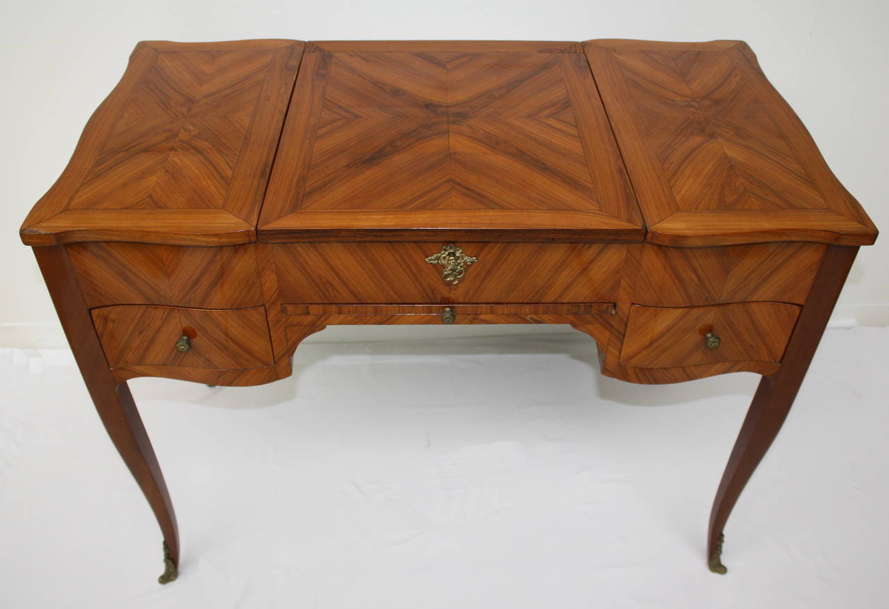 A charming French Coiffeuse in rosewood. The central section with Mirror lifts back, the sides are folding, two drawers.