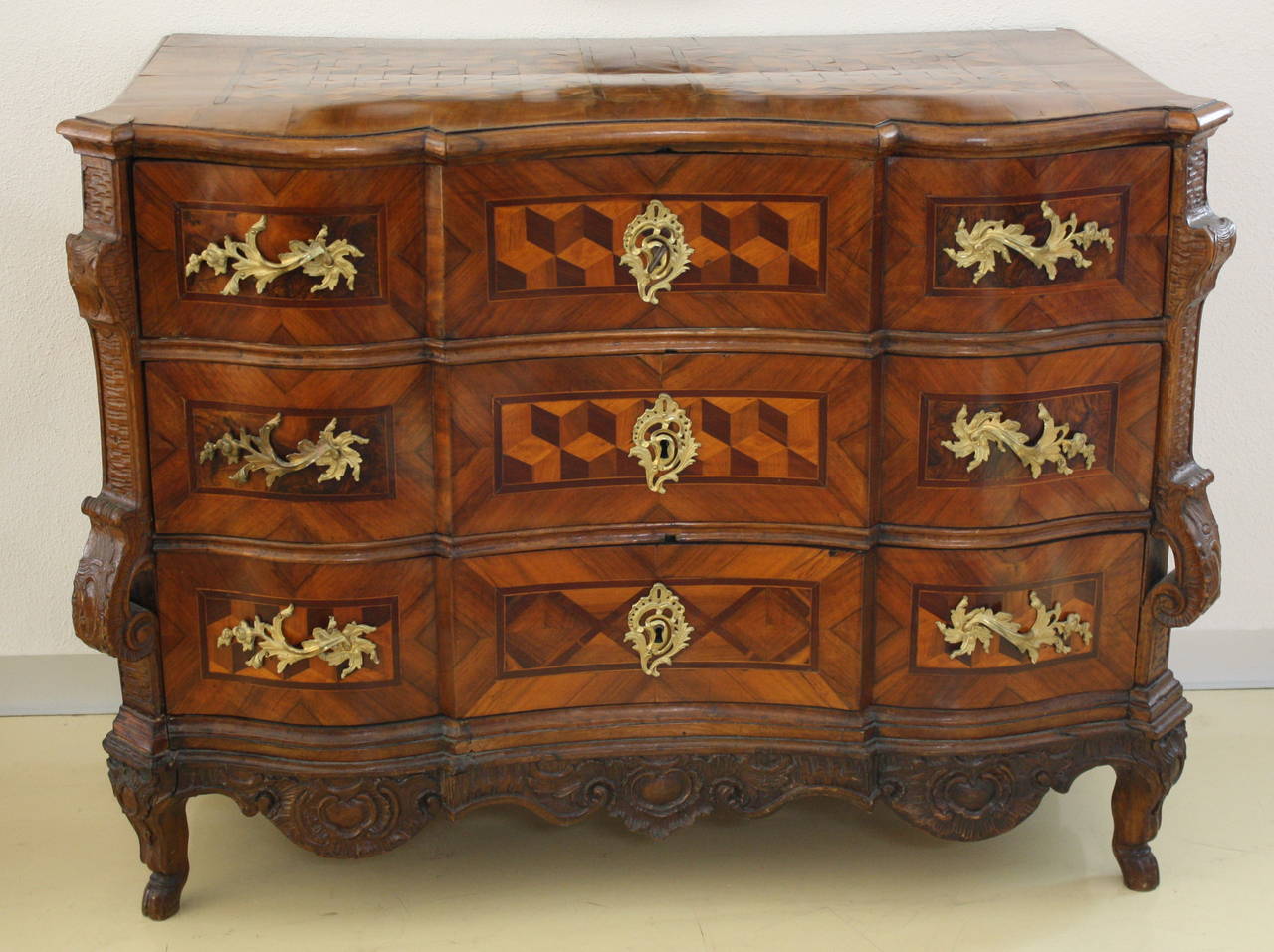 A Baroque three-drawer chest with cube marquetry in field, sides carved and bronze fittings. Original patina.
