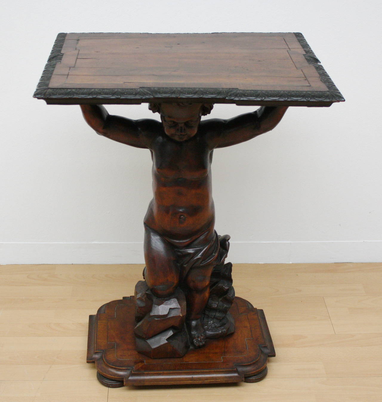 A historism table "gueridon." Carved putti on a base hold the tabletop, table edge carved.