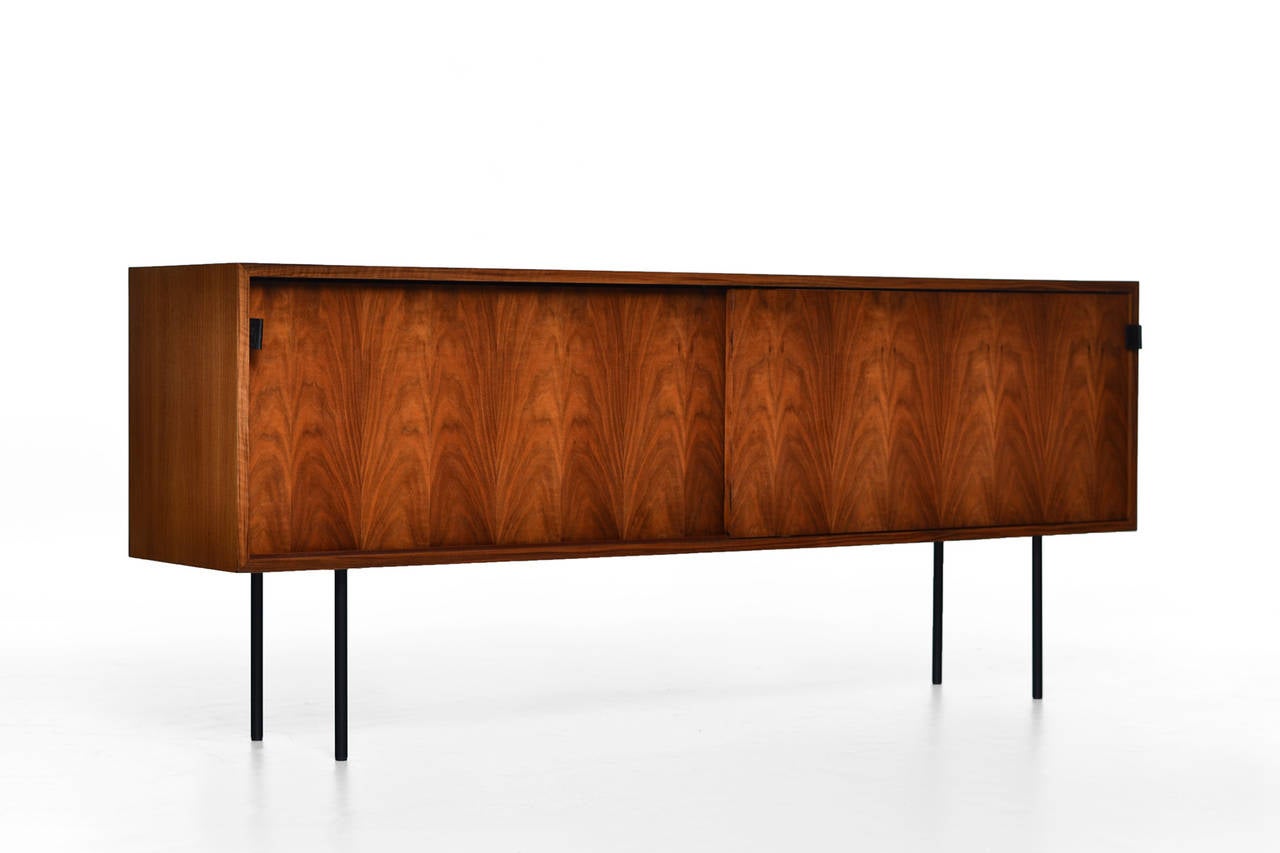 Beautiful credenza by Florence Knoll for Knoll International, US 1950s. Made of Walnut with a lovely woodgrain. Beautiful sophisticated details like the black leather pulls, the hairpin legs and the miter made corners. Fully restored and
