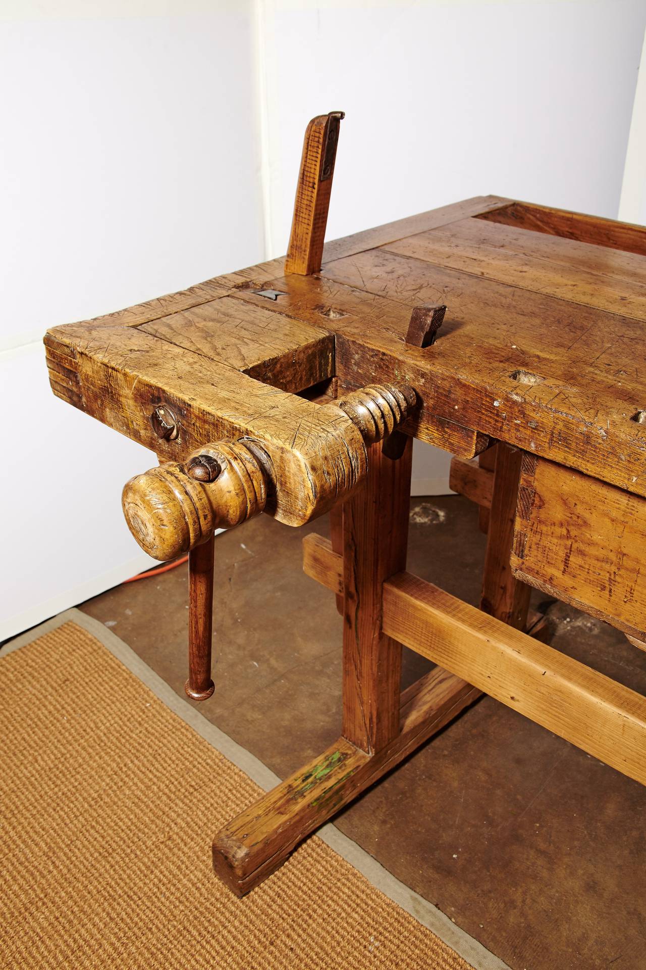 Original working wooden vises on European carpenter's pine and mixed hardwood workbench, circa 1900. Trestle base is held with stretcher/mortice wedge. Recessed tray in back. Dovetailed joinery on the front drawer as well as the corners of the