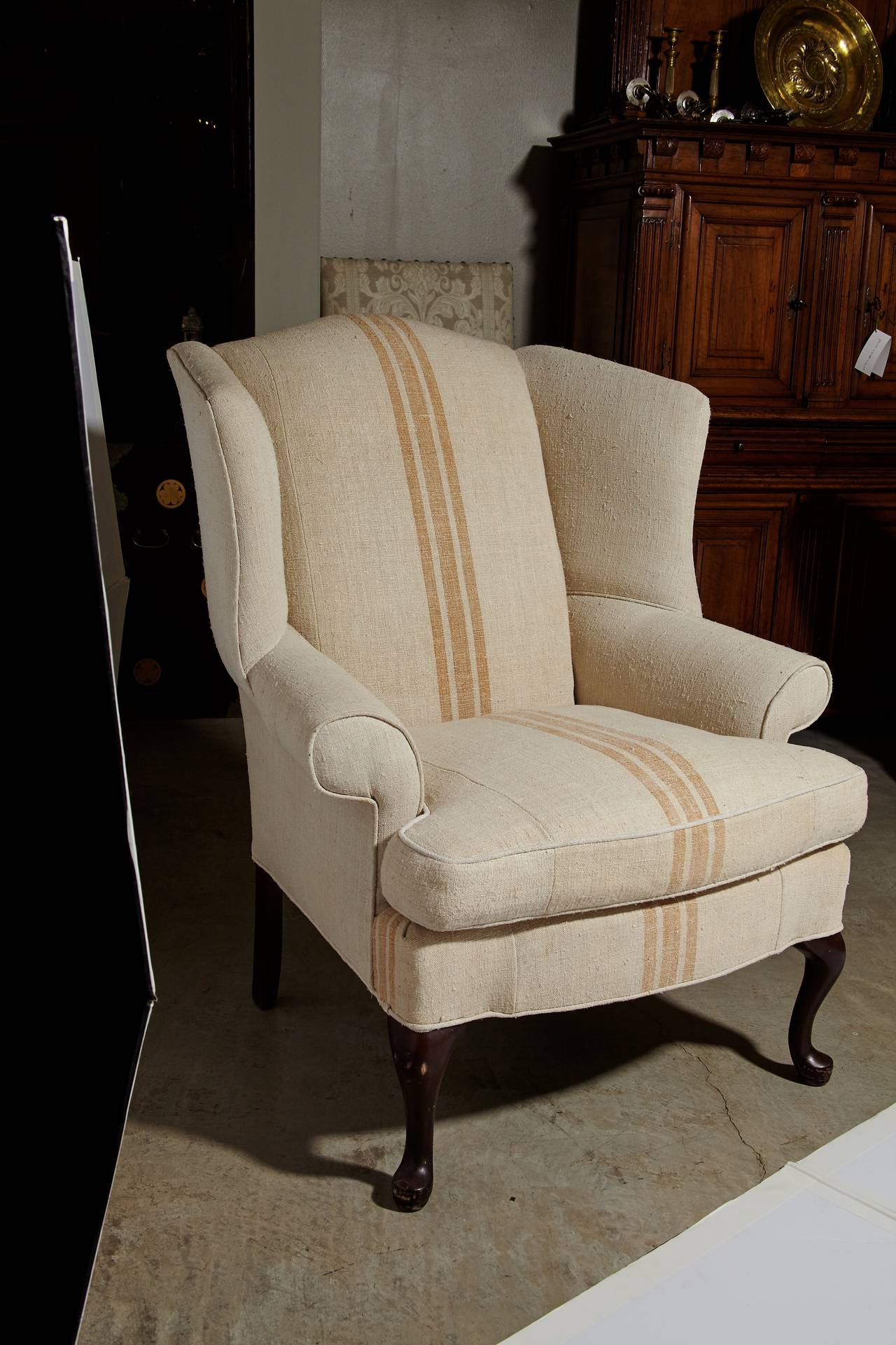 Wonderful pair of wingback chairs that have been upholstered in heavy weight antique homespun Belgian linen flax. circa 1900. Very clean, soft and in excellent condition. The fabric has three umber colored stripes running down the center of the