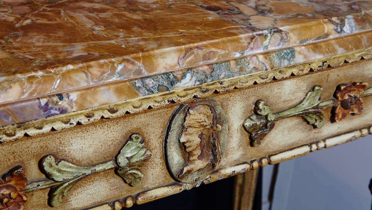 A rare 18th century, Italian carved wood console decorated with relief carvings and painted in the Etruscan manner. The console retains much of its original paint surface in pastel shades of green, orange, yellow, and blue on a crème colored