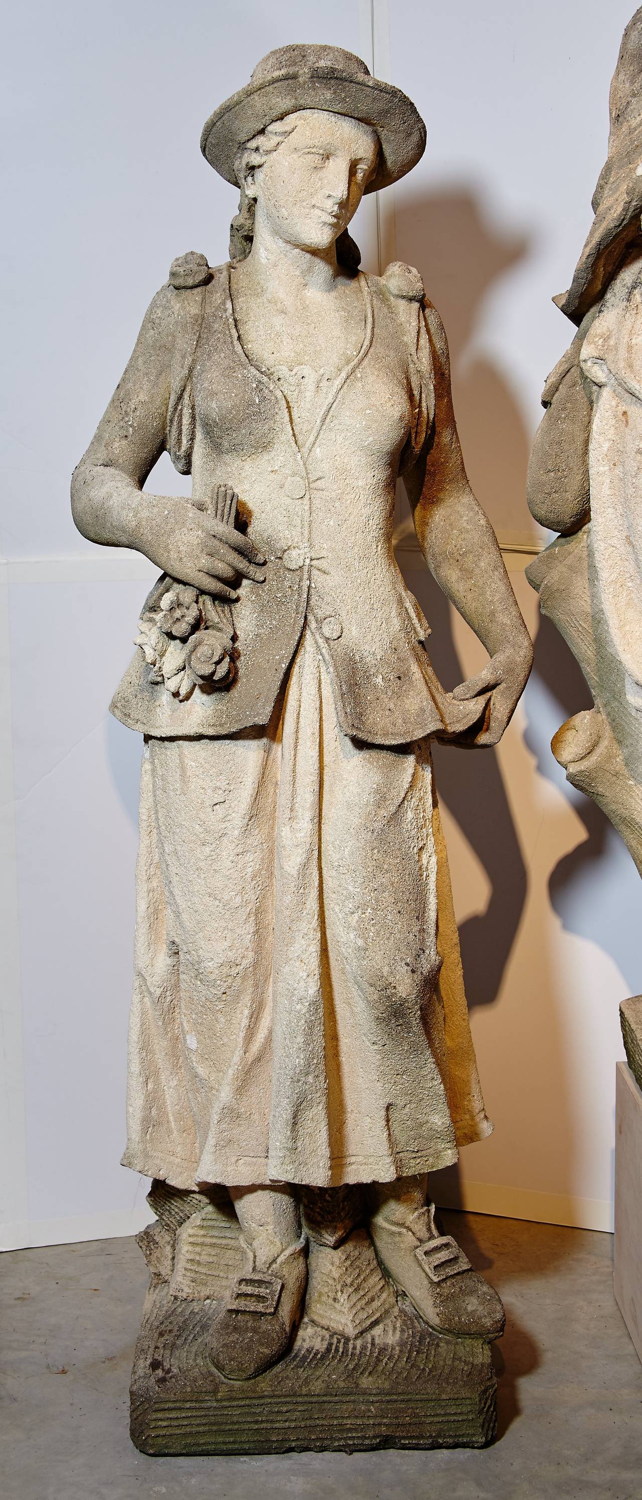 Magnificent hand-carved Vicenza stone statues of young couple dressed in Provincial 18th century garb engaged in pastoral pursuit, him playing a type of shepherd's bagpipe and her holding a bouquet of flowers.