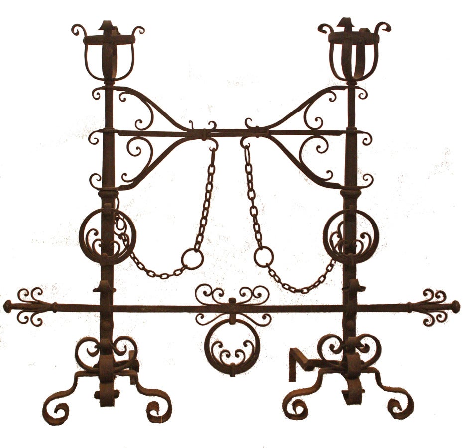 Monumental Gothic Inspired andirons with two swing arms. Graceful pealed petal motif in circle as knocker and on crossbar.