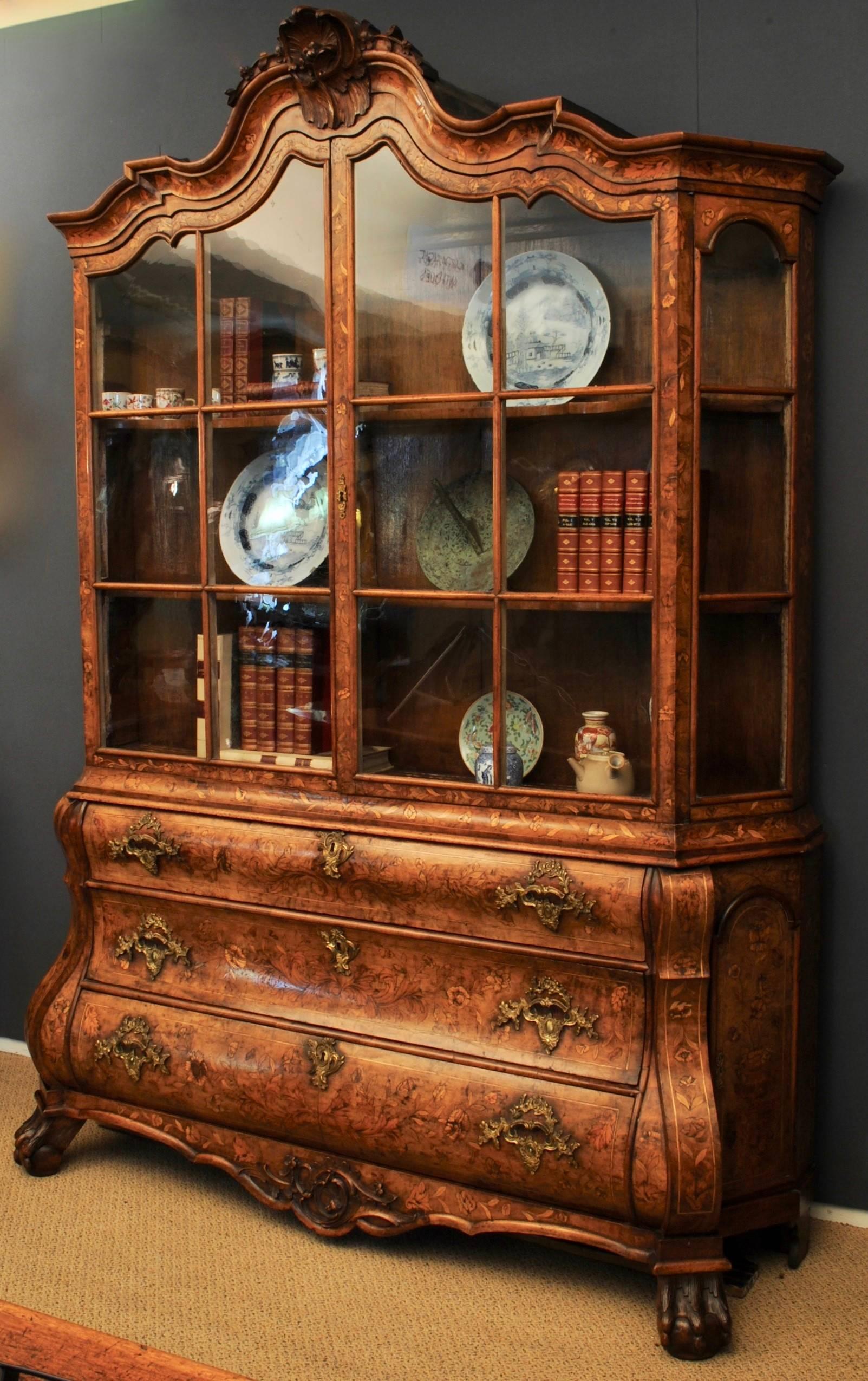 A good example of a late 18th century bombe fronted walnut and floral marquetry two door glazed cabinet, the drawers all retaining the original ormolu handles and raised on carved ball and claw feet. the cornice with caved shell details. Good color