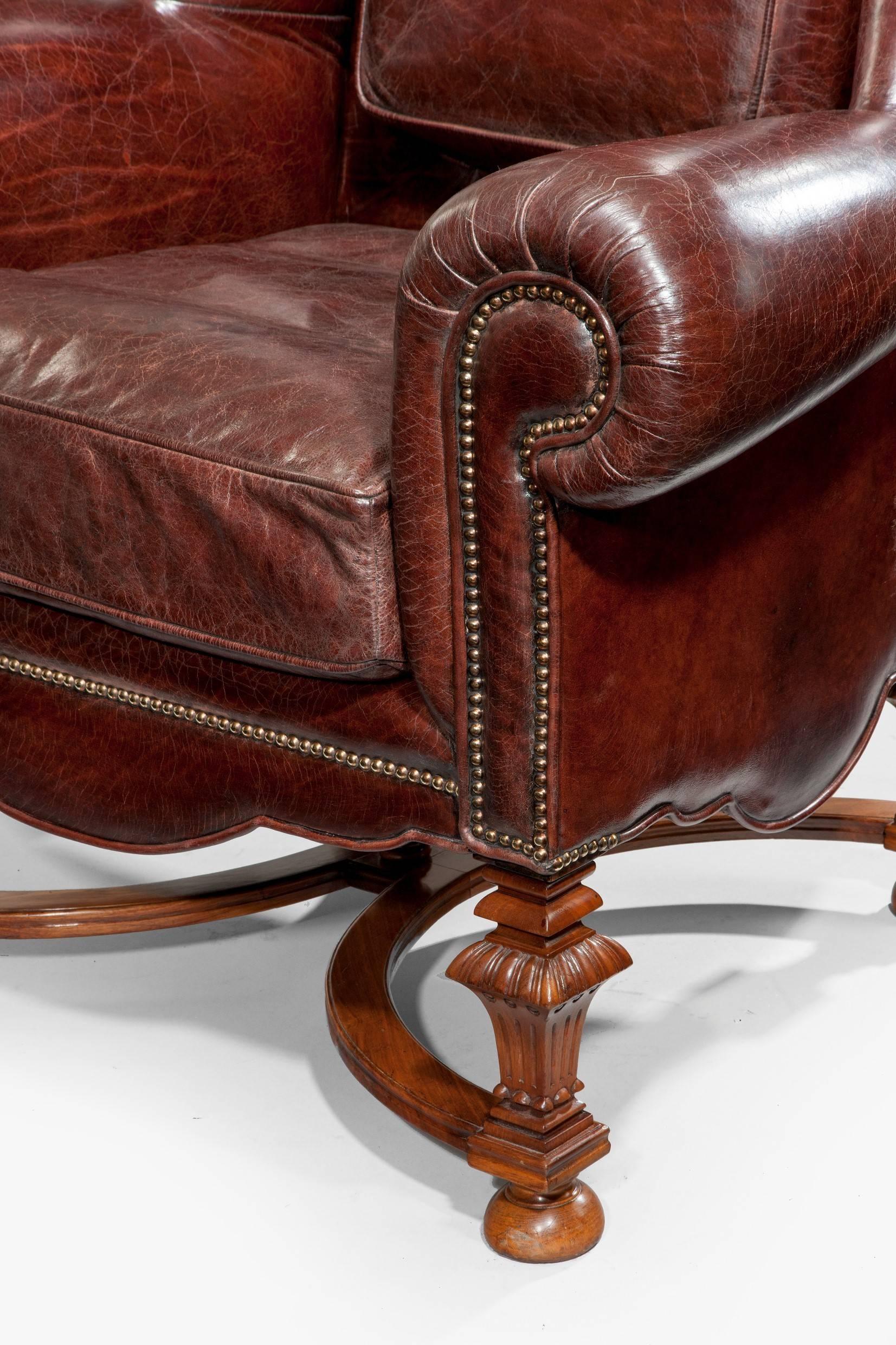 A very grand pair of oversized gentlemen’s walnut wing armchairs, reupholstered in distressed leather.