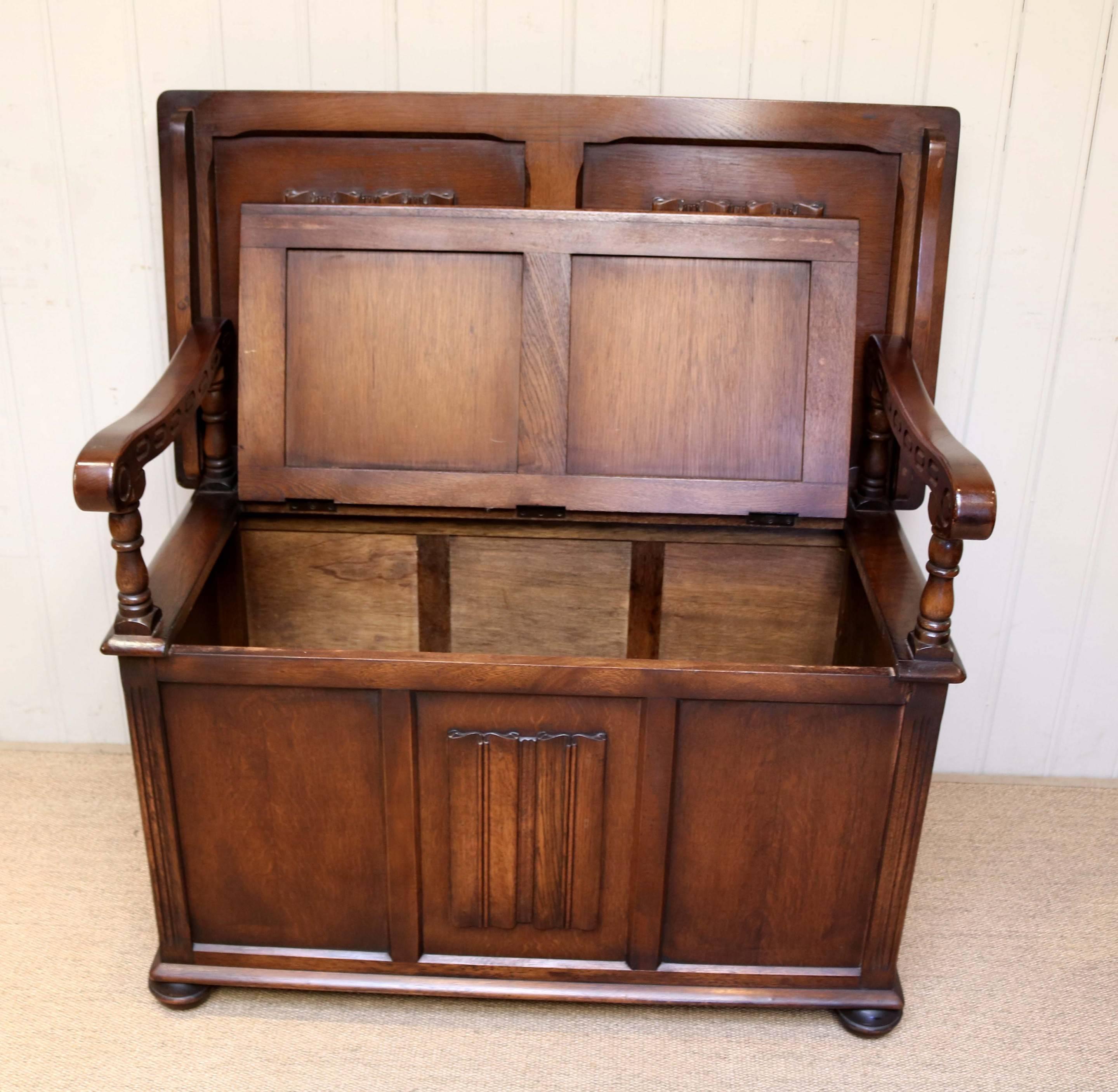 Oak monks bench with linenfold panels to the back and base having a lift up seat for storage .The top folds to become a table with carved wooden arm supports and raised on bun feet. The height when closed is 78 high.