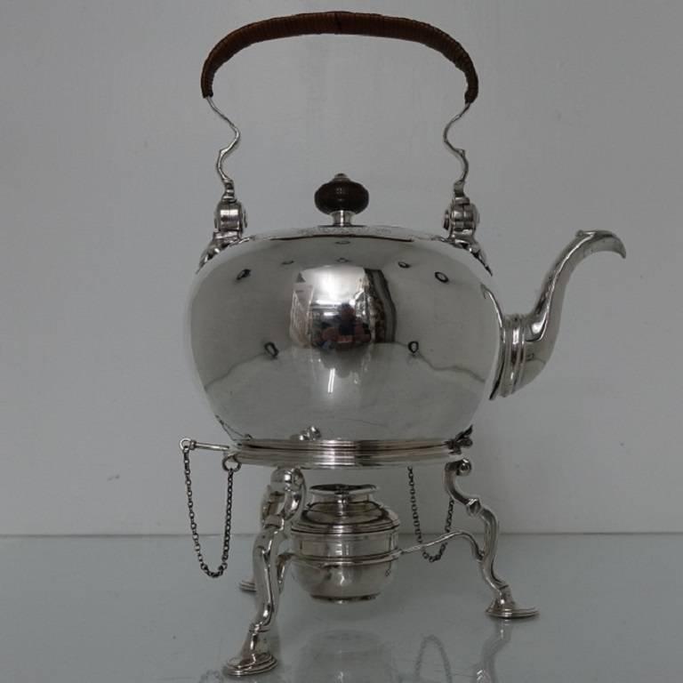 A stunningly beautiful George II kettle on stand, plain formed in design with an elegant contemporary coat of arms for importance. The kettle has a swing hinged wicker handle for easy use and has elegant hand engraving around the hinged lid for